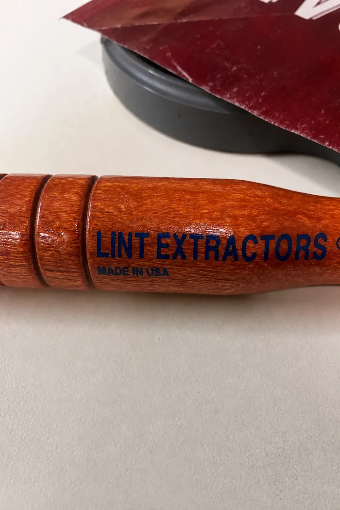 The wooden brush handle stamped Lint Extractors, Made in USA